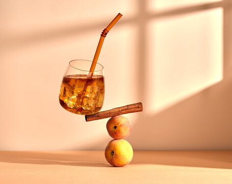 Glass of refreshing cocktail with cinnamon and peaches on table