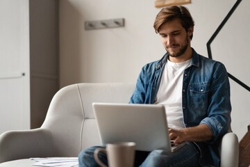 Successful entrepreneur smiling in satisfaction as he checks information on his laptop computer while working
