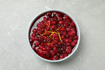 Fresh cranberry sauce with orange peel on light marble table, top view