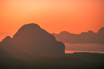 Obraz premium The natural background of the morning light rising in the middle of the sea and surrounded by mountains, cool breezes, the beauty of the ecology of the tourist attractions.