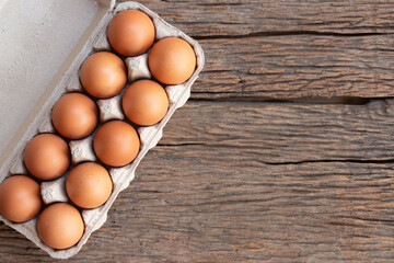 Chicken eggs, brown eggs in carton box on wooden rustic table. Top view eggs in carton box.