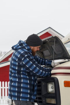 Bearded mechanic checking engine of van