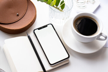 Fototapeta na wymiar White home office tabletop with smartphone mock-up, coffee cup and notepad