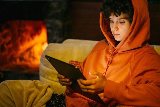 Woman with iPad near fire place.