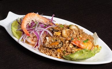 Peruvian traditional food. Seafood with rice decorated with red onion, lettuce. Arroz con mariscos
