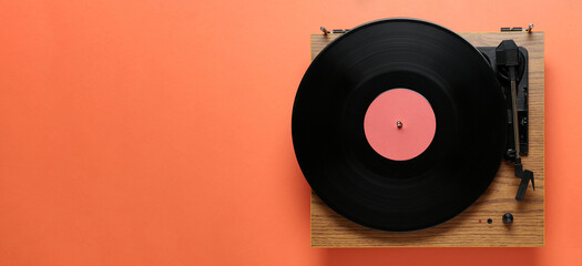 Modern turntable with vinyl record on coral background, top view