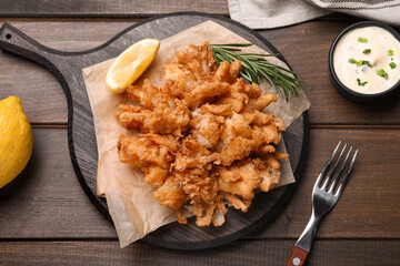 Fried blooming onion with dipping sauce served on wooden table, flat lay