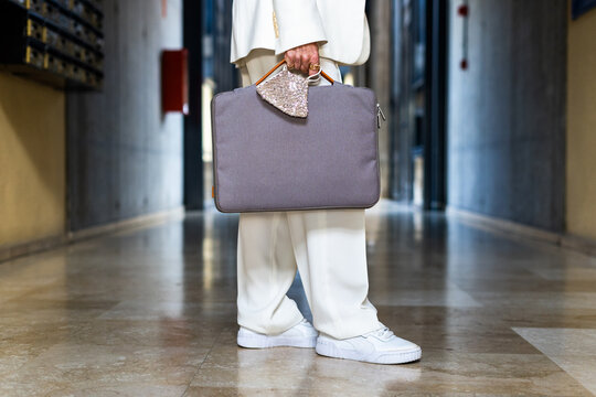 senior business woman leaving her workplace. detail of attache case and mask