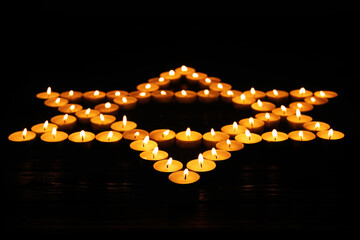 Star of David made with burning candles on black background. Memory day