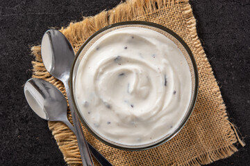 Stracciatella yogurt with chocolate chips in transparent bowl on black background. Top view