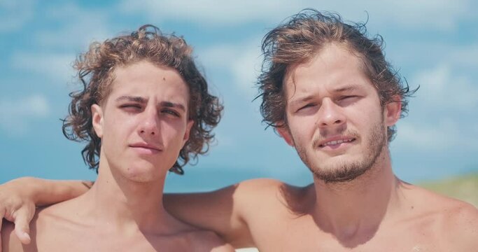 Portrait of Brazilian surfers. Two young Brazilian men stand together on the beach and look at the camera during bright sunny day