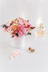 Bouquet with roses, peonies and hydrangea in pink colors. Stabilized flowers in a white ceramic vase at home on the dressing table. Interior decor.