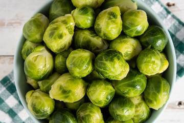 Set of brussel sprouts in a bowl on white wooden table