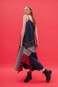 Model posing in plaid dress by red background