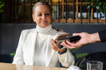 senior business woman paying with mobile phone at restaurant