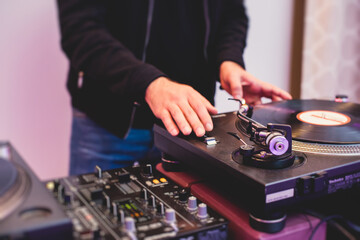 Naklejka premium View of Dj mixer and vinyl plate with headphones on a table with DJ playing and mixes the track in the background, during night techno party in the nightclub