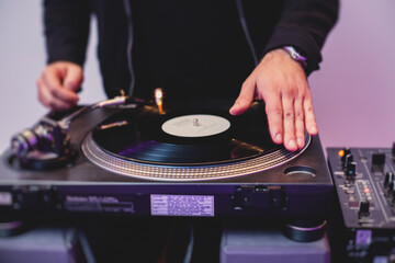 Obraz premium View of Dj mixer and vinyl plate with headphones on a table with DJ playing and mixes the track in the background, during night techno party in the nightclub