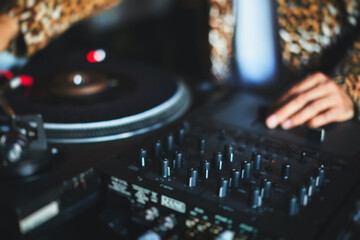 View of Dj mixer and vinyl plate with headphones on a table with DJ playing and mixes the track in...