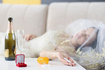 Obraz na płótnie Canvas Bride lying on couch with handful of pills in her hand closeup