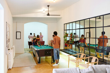 Diverse young people playing pool in a hostel
