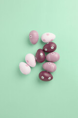 holiday concept. decorative easter eggs of pink and burgundy color. long banner with green background, space for text, top view, vertical frame