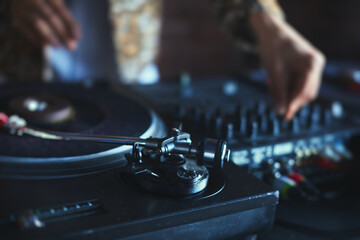 View of Dj mixer and vinyl plate with headphones on a table with DJ playing and mixes the track in...