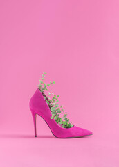 Minimal sustainable fashion concept with high heels and green leaves on pastel pink background. Environmental protection and sustainability idea. Ecofriendly aesthetics. - obrazy, fototapety, plakaty