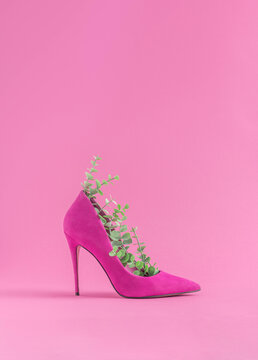 Minimal sustainable fashion concept with high heels and green leaves on pastel pink background. Environmental protection and sustainability idea. Ecofriendly aesthetics.