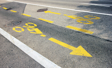 road markings of the bike path in yellow paint with the image of the direction arrows and the cyclist