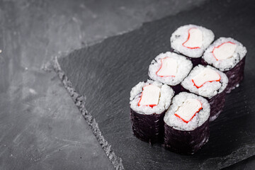 appetizing sushi roll maki with crab stick on a black stone plate © Narsil