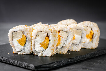 appetizing sushi roll california with tofu cheese and omelet on a black stone plate