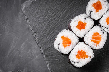 appetizing sushi roll maki with salmon on a black stone plate