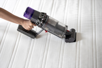 Frühjahrsputz im Schlafzimmer, Staubsauger saugt die Matratze ab und befreit sie so von Milben