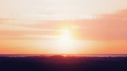Amazing aerial view from a watchtower over the endless forest and lake at sunset. 16x9