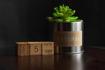 November 15. Image of the calendar November 15 wooden cubes and an artificial plant on a brown wooden table reflection and black background. with empty space for text