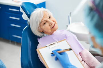 Dental surgeon writing in her notepad before pensioner