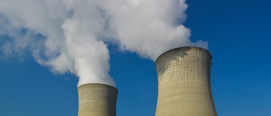 Fumée blanche de vapeur d'eau sortant de deux cheminées d'une centrale nucléaire sur fond de...
