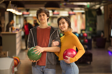 Young couple having fun in bowling alley.  Portrait of smiling couple. Holding a bowler.
