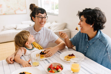 Obraz na płótnie Canvas Female couple with son having breakfast
