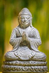 Obraz premium Buddha statue with green natural background, as buddha sitting and meditating with praying hands