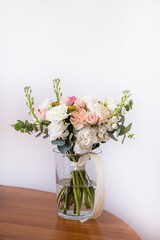Beautiful wedding bouquet on bright background. Bouquet consists of pink roses, ranunculus, eucalyptus