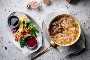 Top view on vietnamese traditional soup pho bo with sauces and toppings