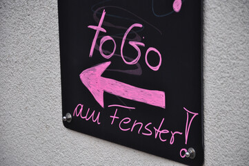 To Go, eine schwarze Tafel mit pinker Aufschrift und Richtungspfeil.
