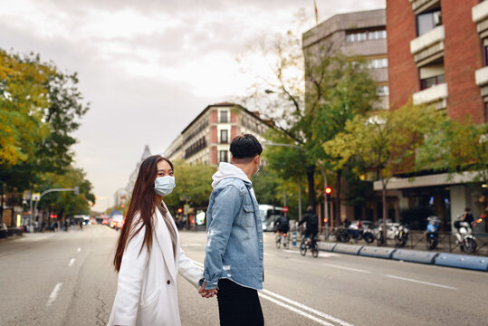 Chinese couple crossing an empty street holding hands