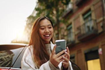 Asian woman laughing while using a mobile phone