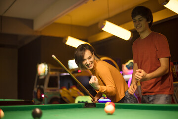 Young couple spending time in billiard room. Woman is a winner.