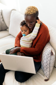 Mother using laptop while hugging her daughter