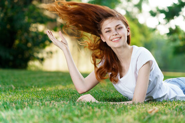 Obraz premium cheerful woman lying on the grass fresh air park leisure lifestyle freedom