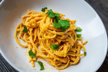 Creamy vegan linguine pasta in cherry tomatoes and cashew sauce. Tasty and fresh Italian dish with garlic, olive oil, and herbs. Authentic Italian cuisine with gluten free spaghetti ready to eat.