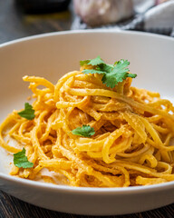 Creamy vegan linguine pasta in cherry tomatoes and cashew sauce. Tasty and fresh Italian dish with garlic, olive oil, and herbs. Authentic Italian cuisine with gluten free spaghetti ready to eat.